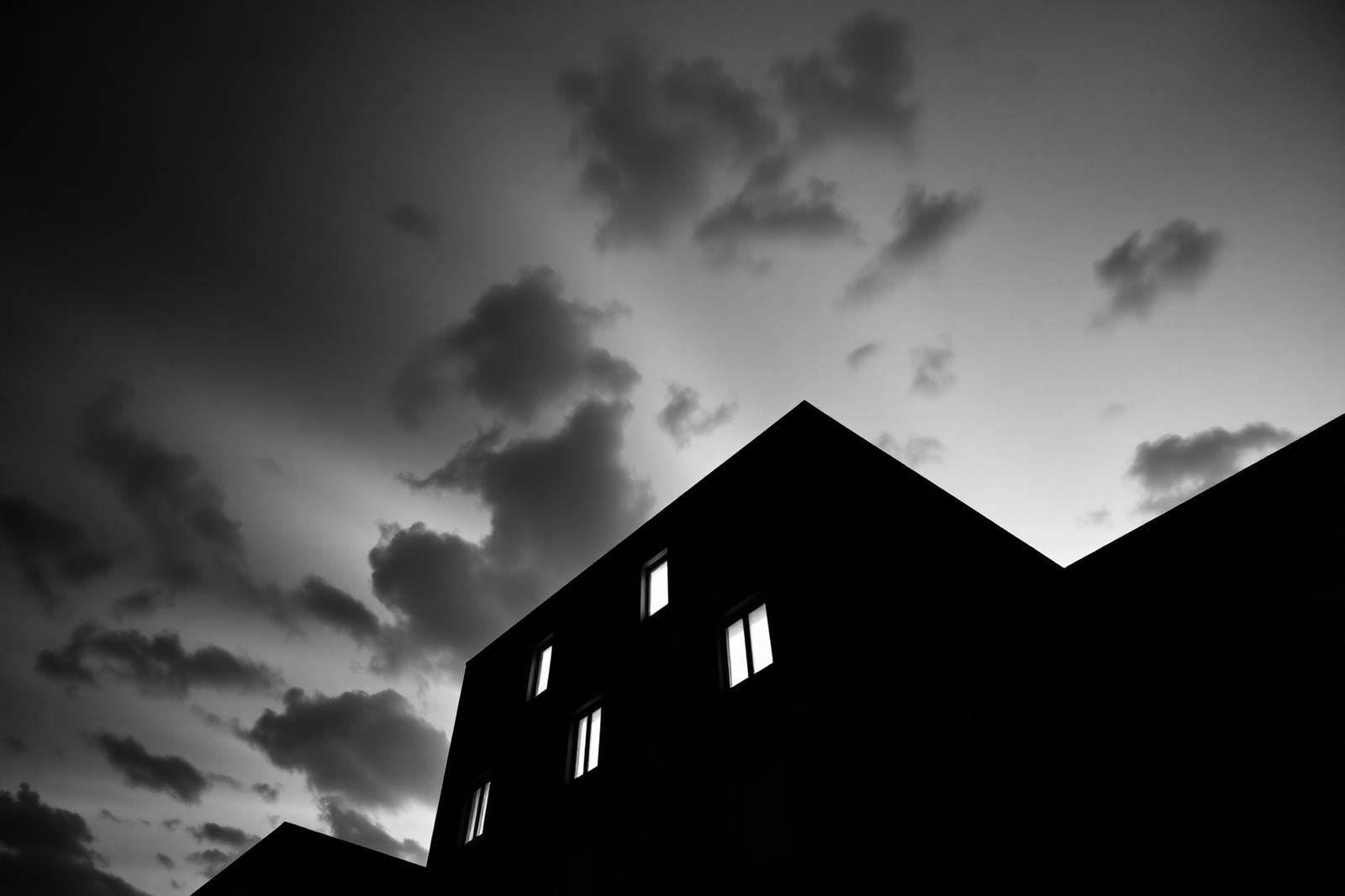 Dark modernist facade at dusk with lit windows