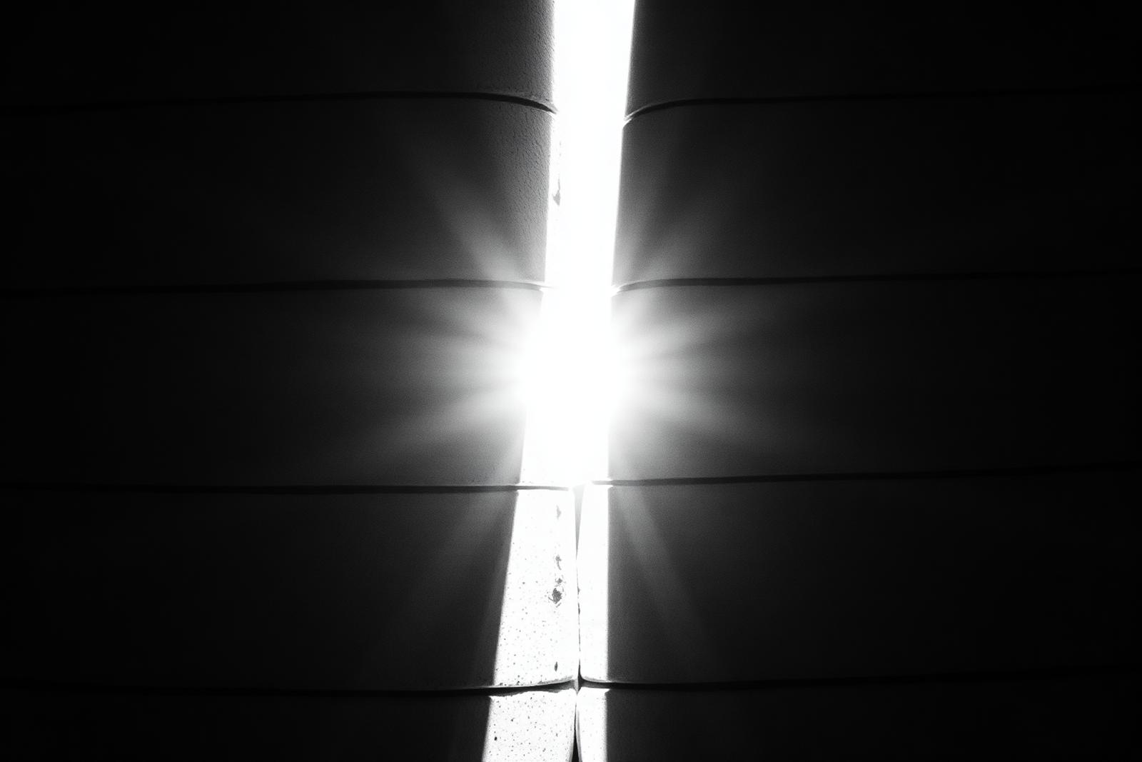 Board-formed concrete wall split by a shaft of light