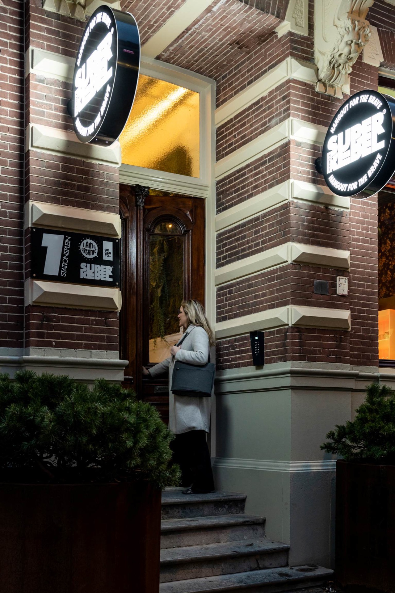 Illuminated round SUPER REBEL signs beside the front door of Hotel SuperRebel