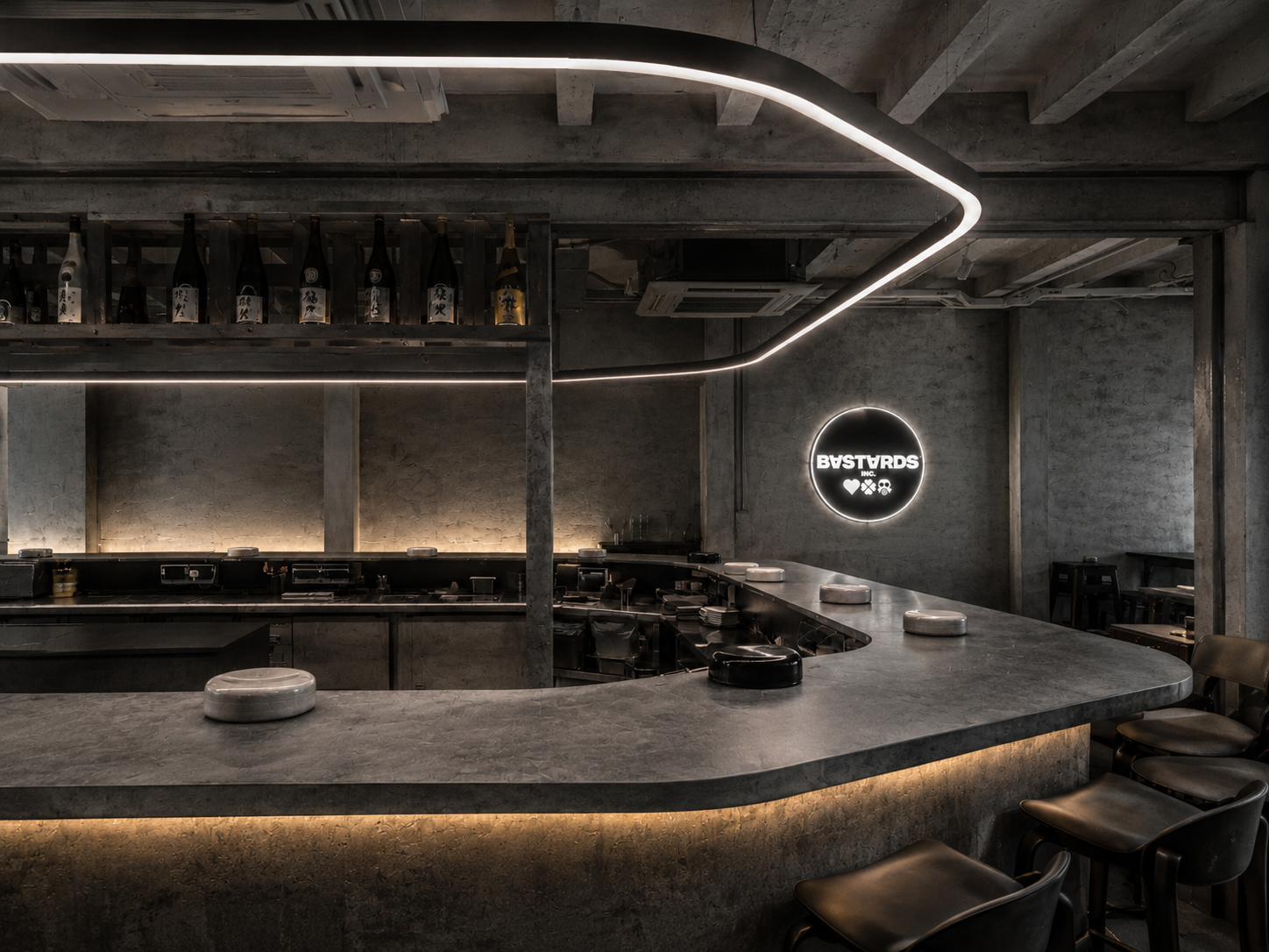 BASTARDS INC.® bar — concrete interior with neon signage and sake wall